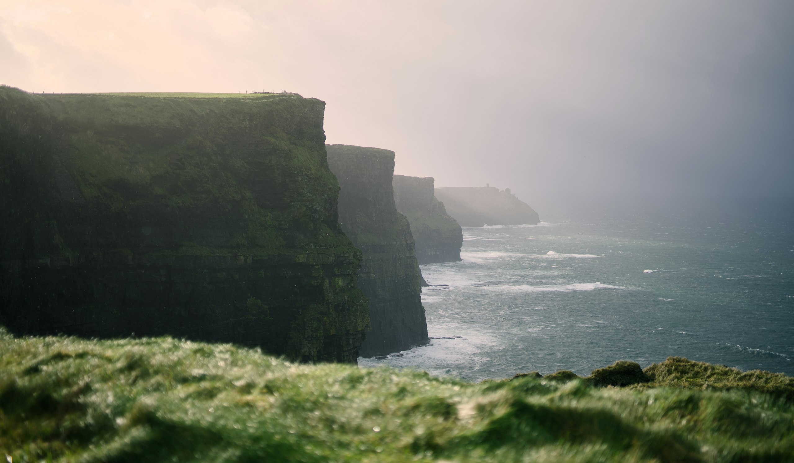 A walker standing at the edge of a cliff above the ocean